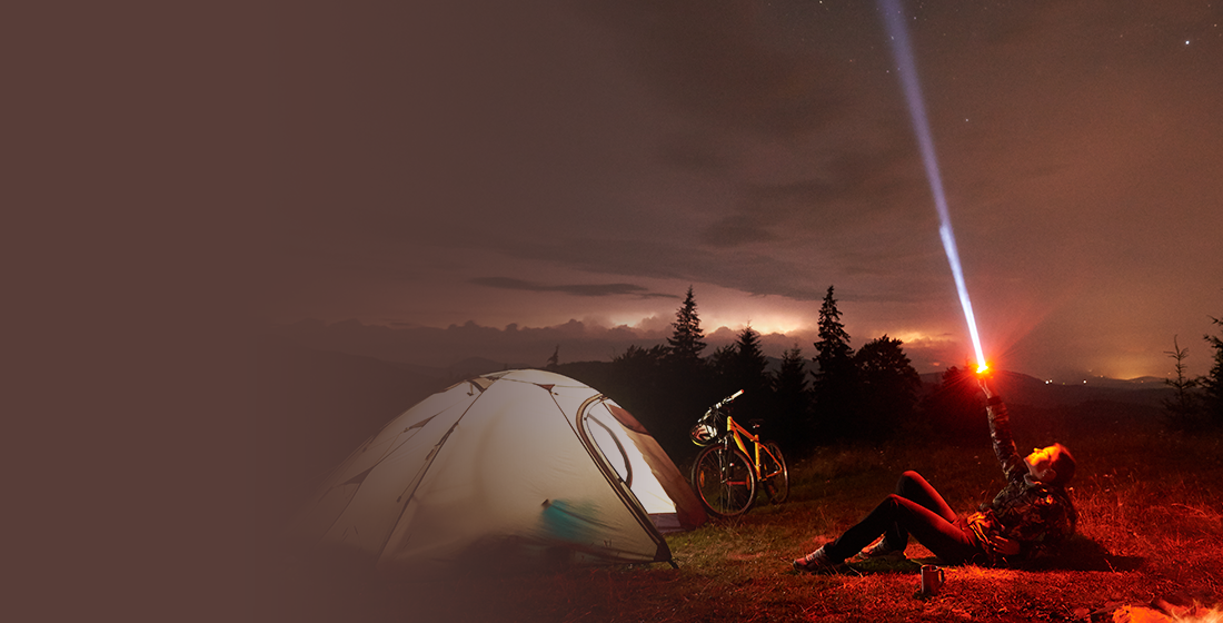 Official Tactical Flashlight image of the beam lighting the night sky at a campsite